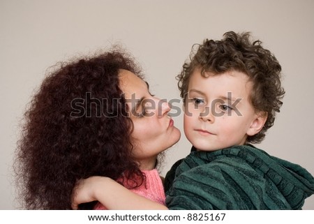 Mother kissing her son. Indoor scene.