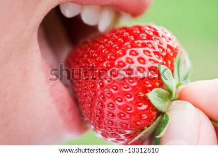 Woman biting a juicy delicious strawberry