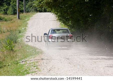 Silver car at high speed on a country-side road without pavement