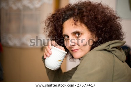 Redhead woman with curly hair drinking coffee from a cup, very shallow depth of field