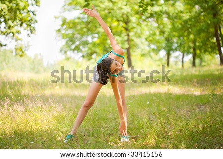 Young sporty lady doing aerobics or yoga outdoors in a forest. Sport and healthy life concept.