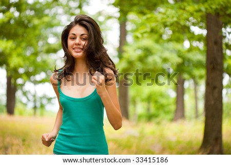 Beautiful young woman running or jogging through a forest, healthy life and sport concept