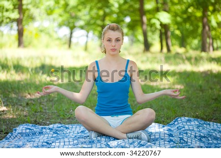 Pretty young blonde girl doing aerobics or yoga outdoor, in the forest
