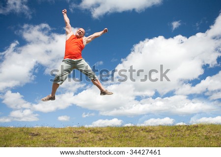 Young man jumping for joy in a beautiful landscape with blue sky and clouds