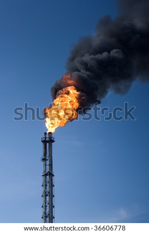Refinery funnel burning with huge flame and throwing clouds of dark smoke