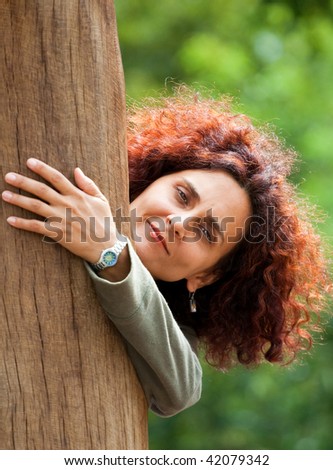 Attractive young lady playing peek-a-boo outdoors