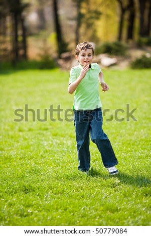 9 years old boy running on a meadow in a sunny day