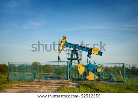 Industrial landscape with an oil pump at sunset