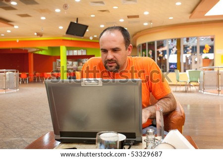 Casual dressed businessman in a restaurant working at his laptop