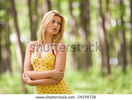 Beautiful blonde woman in yellow dress in the forest