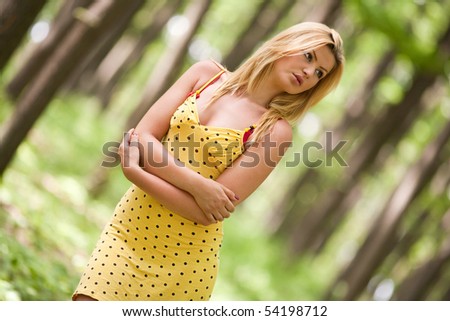 Beautiful blonde woman in yellow dress in the forest