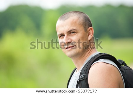 Close up of a young man with backpack and t-shirt hiking into the woods