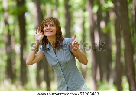 Beautiful young woman relaxing in the forest and listening nature sounds