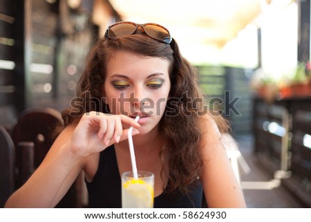 Woman drinking soda with a straw, in a restaurant
