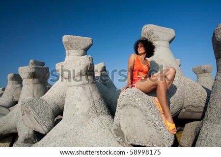 Young lady sitting on rocks on a dam at the sea side
