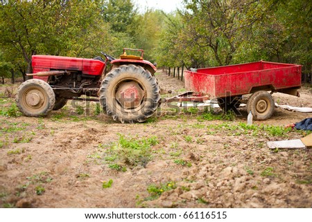 Old beaten tractor and trailer in an orchard