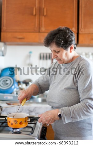 Senior woman cooking on a stove in bright daylight