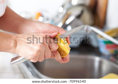 Woman\'s hands closeup, peeling potatoes in the kitchen