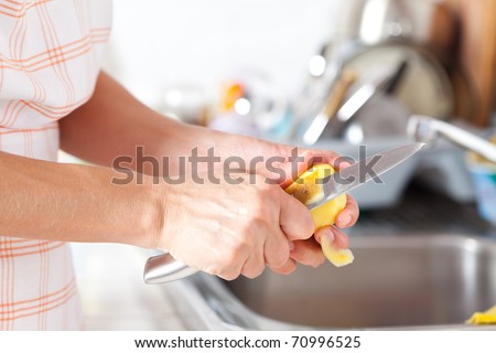 Woman\'s hands closeup, peeling potatoes in the kitchen