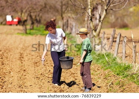 Young mother and son farmers planting seeds mixed with fertilizer