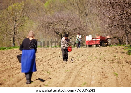 Family of farmers sowing seeds mixed with fertilizer on their land