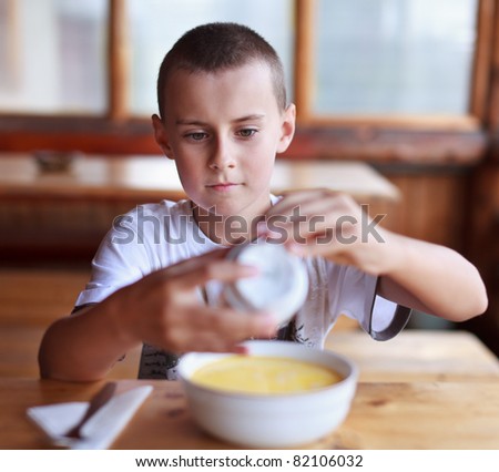 Boy eating soup for dinner in a rustic restaurant outdoor