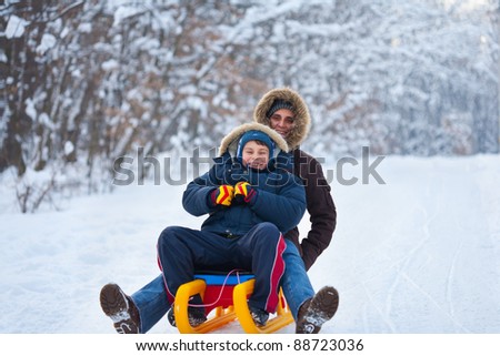 Mother and son riding a sledge in a holiday winter day