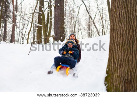 Mother and son riding a sledge in a holiday winter day