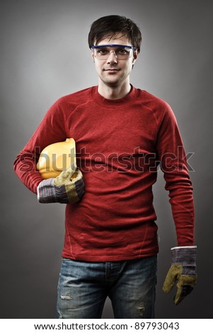 Young blue collar worker with yellow protective helmet and gloves