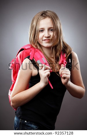 Closeup studio portrait of a blond schoolgirl with pink backpack on gray background