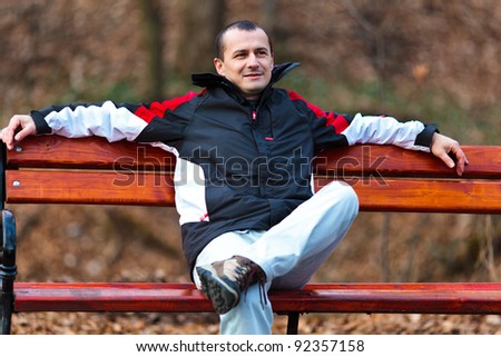 Relaxed young man sitting on a bench in park