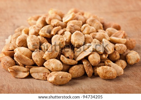 Macro of salted and roasted peanuts on a wooden board