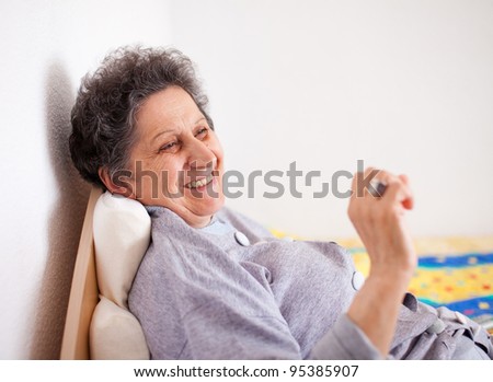 Indoor portrait of a senior woman sitting on bed, resting