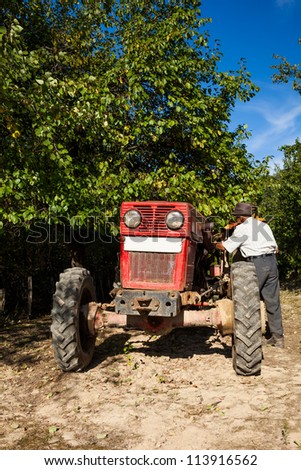 Senior farmer near his tractor in an orchard