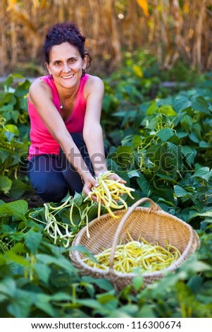 Portrait of a young woman picking bean pods in the countryside