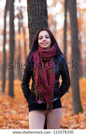 Closeup portrait of a beautiful young woman leaning on a tree trunk in the woods