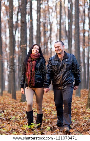 Full length portrait of a happy couple walking in the woods while holding hands