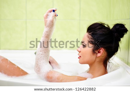 Young brunette woman in the bath tub with foam, relaxing