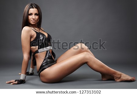 Close-up profile of hot exotic dancer in leather lingerie sitting on the ground, facing the camera
