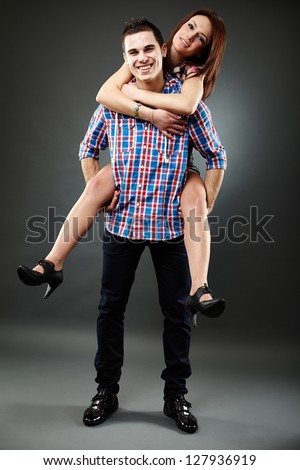Happy young couple with piggyback ride, studio shot