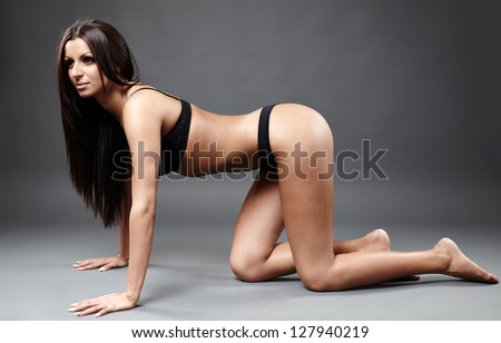 Full length profile of hot exotic dancer in sexy lingerie sitting on hands and knees on the ground