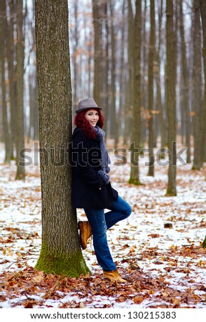 Young girl in outdoor full length, propping on a tree in a forest