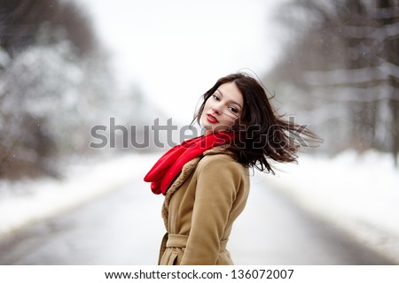Portrait of a beautiful brunette with hair blown by wind in the winter