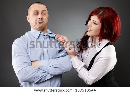 Portrait of a businesswoman pulling businessman\'s necktie