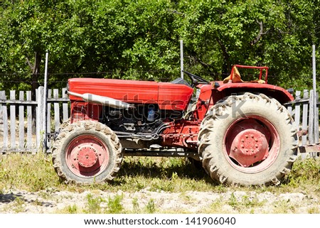 Old red tractor in an orchard in the daylight