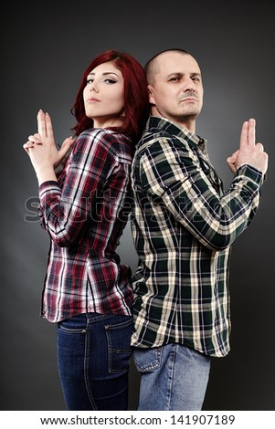Young couple back to back standing with imaginary guns