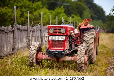 Old red tractor in an orchard in the daylight