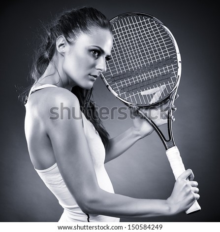 A monochrome studio shot of a young female tennis player holding the racket
