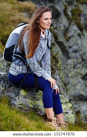 Woman hiker with backpack resting on a rock
