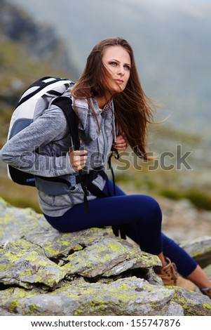 Woman hiker with backpack resting on the mountain rocks